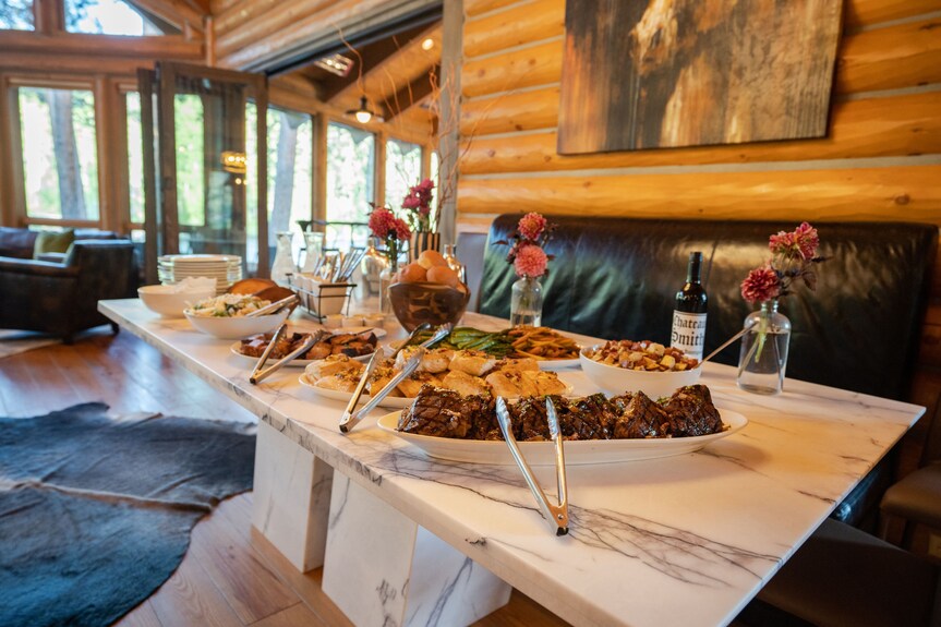 Lodge dinner spread with grilled meats, sides, and wine in the main lodge dining area