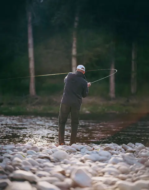 Fly casting from the rocky shore at golden hour