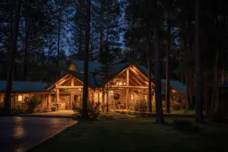 The Bitterroot Mile Club lodge glowing at twilight among the pines
